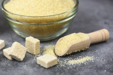 Şeker küpleri ve bir yığın esmer şeker kasede ve ahşap kepçe üzerinde 