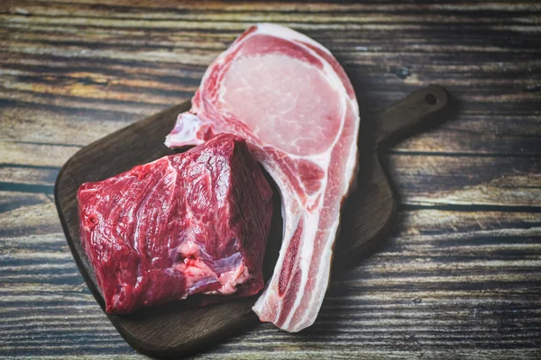 Fresh meat beef sliced and pork chops on wooden cutting board ba — Stock Photo, Image