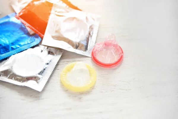 Kontrol kelahiran dengan kondom berwarna-warni pada kehamilan latar belakang kayu — Stok Foto