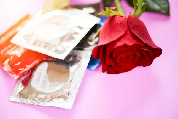 Kontrol Kelahiran dengan kondom dan mawar cinta bunga di backgrou merah muda — Stok Foto