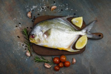 Bitkilerle taze pomfret balığı baharat biberiye domates ve limon.