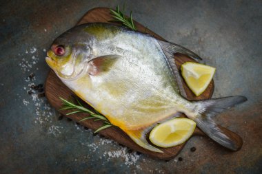 Otlu taze pomfret balığı baharat biberiye ve limon.
