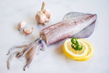 Salata soslu çiğ kalamar. Beyaz tabakta limon sarımsağı.