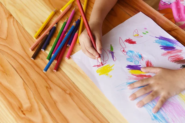 Meisje schilderen op papier vel met kleurpotloden op de houten t — Stockfoto