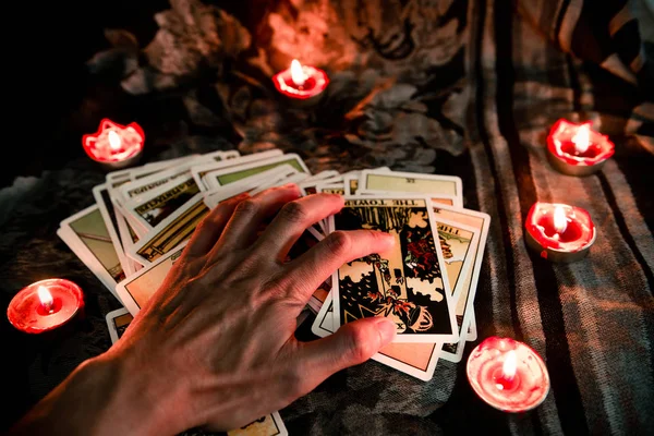 Mano en la tarjeta del tarot con la luz de las velas en el fondo oscuro f — Foto de Stock