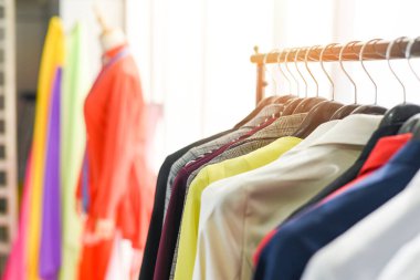Woman fashion clothes of different colors clothing on hangers at the showroom / Hanging clothes suit colorful or closet rack 