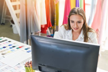 Tekstil malzemesi makaslarını ölçen moda tasarımcısı masa masası genç bir kadın tasarımcının kumaşını kesiyor stil tasarımcısı elbise asıyor bilgisayar tasarımcısı bilgisayar bilgisayarı tasarımcısı