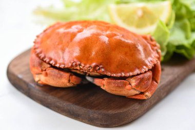 Crab cooked steam or boiled with lemon and lettuce salad vegetable on wooden board in a restaurant / Fresh seafood stone crab