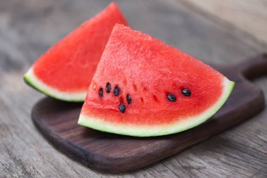 Sliced watermelon on wooden cutting board background / Close up fresh watermelon pieces tropical summer fruit 