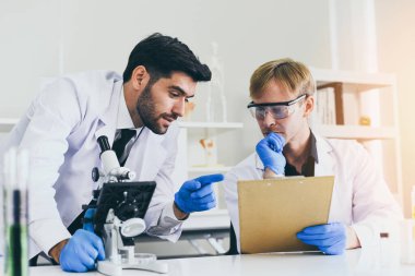 Bilim adamlarından oluşan bir ekip, laboratuvar biyokimya, genetik, mikrobiyoloji ve test tüpü erkek doktoru laboratuvarında birlikte deneyler yapıyor ve mikroskop inceliyor.