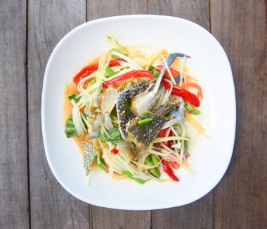 Papaya salatası, mavi yengeç / Tayland yemeği, çiğ yengeç, baharatlı deniz ürünleri ve sebze, ahşap masa, üst manzara.