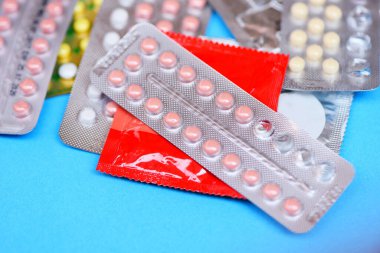 Mavi arka planda doğum kontrol hapları ve prezervatif hamileliği veya cinsel yolla bulaşan hastalıkları önler.