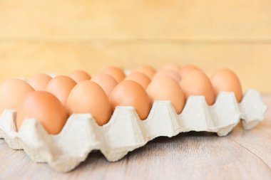 Tahta arka planda yumurta kutusundaki yumurtalar. Çiğ tavuk yumurtalarını organik gıdalara yakın tut. 