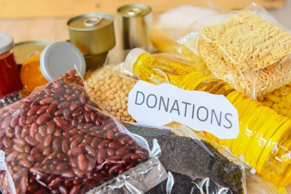 Donations food with canned food on wooden table background / pasta canned goods and dry food non perishable with pea beans cooking oil instant noodles macaroni , donate concept
