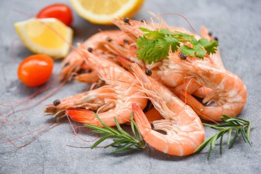 Karanlık tabakta taze karides, baharat, baharat ve karides karışımı bir masa arkasında servis ediliyor.