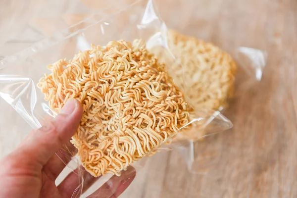 instant noodles in package in hand / dry food non perishable storage goods in kitchen home or for donations