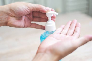 Kadınlar ellerini alkol jeliyle veya antibakteriyel sabun dezenfektanıyla yıkıyor / Bir şişe antibakteriyel dezenfektan kullanan insanlar Covid-19 Coronavirus kavramının temiz el hijyen önlemini ovuyorlar