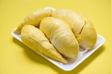 Plastik tepsideki ağaç kabuğundan taze Durian meyvesi ve sarı arka plan / Tayland 'da tatlı tatlı tatlı veya atıştırmalık için olgun durian tropikal meyvesi yazı