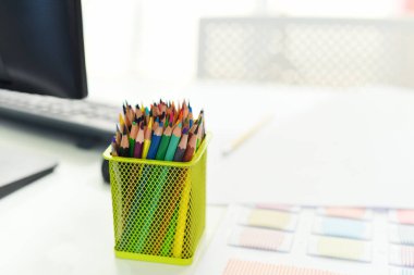 Tasarımcı masası / Tablo çalışma yeri ofis arka planı için renklendirilmiş bilgisayar ve renkli kalemler veya pastel kalemler ile ofiste masa