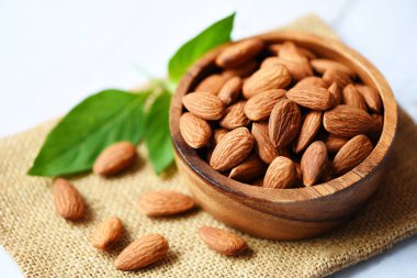 Tahta kasede badem ezmesi, yapraklı badem, arka planda üst görünüm, atıştırmak için kavrulmuş badem.