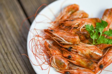 Kızarmış karides kafası lezzetli baharatlar tabakta ve ahşap masa arkasında pişmiş karides veya karides, deniz ürünleri kabuklu deniz ürünleri