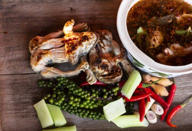 Baharatlı ızgara kurbağa grubu ve ahşap arka planda izole edilmiş baharatlı kızarmış kurbağa.