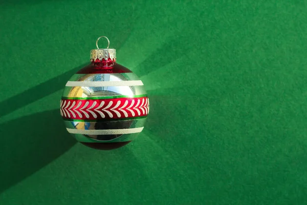 Rot-grüne Weihnachtskugel auf grünem Hintergrund — Stockfoto