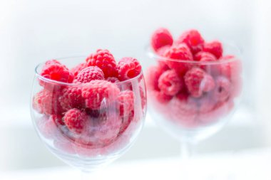 Ahududu çileği yakından. Yazın sulu taze meyveler. Sağlıklı yemek. Böğürtlenler cam bardaklara doldurulur. seçici yumuşak odak.