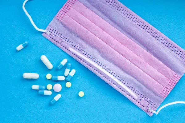 Mavi arka planda, çok renkli haplar ve pembe bir maske var. Farklı boyut ve amaçlara sahip tabletler, küçük ve büyük. Çeşitli hastalıklarda, tabletler bir kopya alanı ile bir arkaplan olarak yerleştirilir.