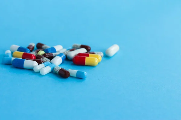 On a blue background multicolored pills. The medicine concept. Multicolored medicines background. Different remedy, pills, capsule, antibiotic and vitamin.