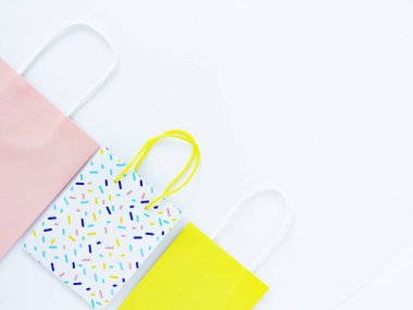 Beyaz arka planda üç tane renkli hediye çantası. Hediyeler, alışverişler ve tatiller.