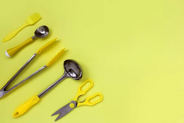 Accessoires de poche de cuisine, ciseaux, pinces, brosse, cuillère à crème glacée jaune sur un fond jaune — Photo