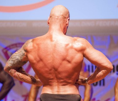 Erkek vücut geliştirmeci kasları şişiriyor ve onun en iyi fiziksel gösterir