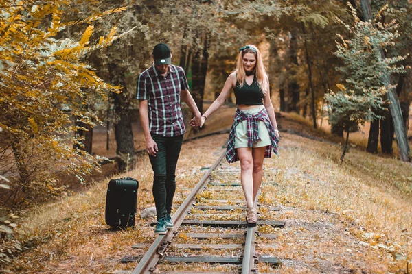 Um jovem casal de amantes perdeu o comboio. Caminhando sobre os trilhos na floresta de outono à espera do próximo trem . — Fotografia de Stock