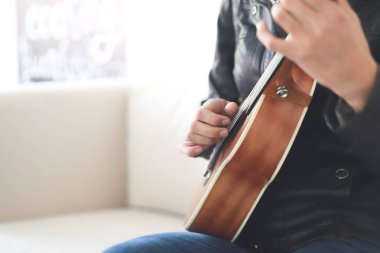 Ukulele çalan genç bir kızın yakın çekimi. Gitar çalan hippi bir kadın, tavan arasında ukulele çalmayı öğrenen mutlu genç bir kız. Metnin için boşluk kopyala.