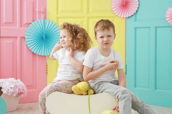 Sarışın kıvırcık kız ve beyaz tişörtlü üzgün çocuk portresi sarı, pembe ve mavi arka planda. Çocuk cinsiyet ilişkileri kavramı. — Stok fotoğraf