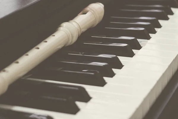 Block flute rest on a piano keyboard. classic music concept — Stock Photo, Image