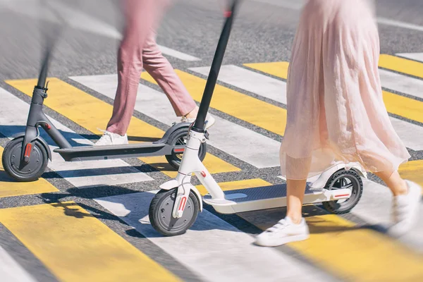 Patas de mujer y piernas de hombre caminando con scooter en cruce de caminos —  Fotos de Stock