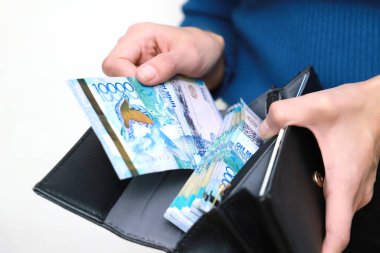 Parayı cüzdanına koyuyor. On bin onluk banknot..