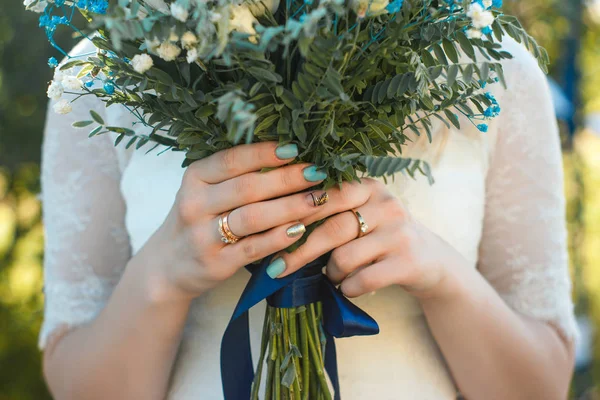 Vista de cerca de los brazos de la novia con el arte de las uñas y el anillo en los dedos con ramo de boda rústico con detalles de color turquesa . —  Fotos de Stock