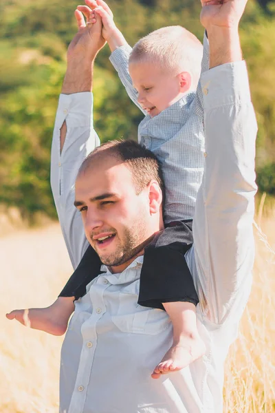 Gelukkige familie met Kid samen wandelen in tarwe veld op warme en zonnige zomerdag. Zachte focus. — Stockfoto