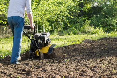 Toprak sürme sürecinde motorlu tarım aracı perspektifinden bakan bir adam