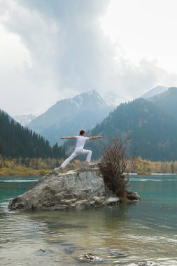 Savaşçı Yogacı Dağ Gölü Kayası 'nda poz veriyor..