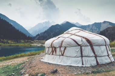 Kazakistan dağlarındaki göl kenarındaki Yurt. Karlı dağ zirveleri.