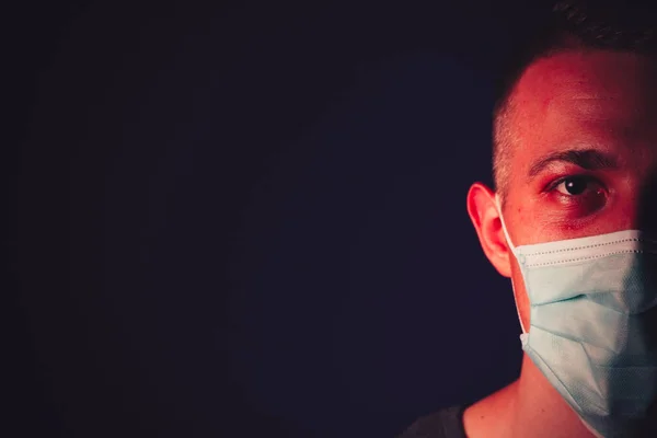 Caucasian man portrait in a medical gauze mask on dark blue background. Virus prevention concept