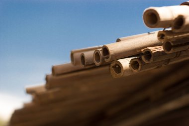 Wicker çatı plaj şemsiyesi ve mavi gökyüzü. Deniz yoluyla sahil adası. Mavi deniz kıyısında doğal bambu güneşlikleri ve yaz şemsiyesi şemsiye. Büyük saman plaj şemsiyeleri.