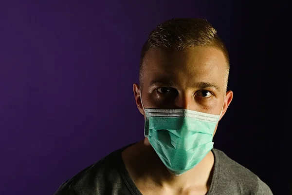 Caucasian man portrait in a medical gauze mask on dark blue background
