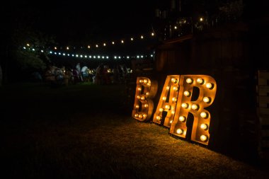 Barın yanında büyük parlak harfler var. Sarı lambalar.