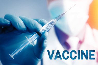 Mavi lateks eldivenli ve şeffaf şırıngalı tıbbi gazlı bez maskeli doktorun elini kapat. Sağlık ve aşı kavramı