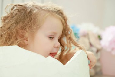 Küçük bir çocuk, beyaz bir yumurtanın içinde oturuyor. Stüdyonun renkli arka planında yeni doğan bir bebek portresi ya da aile konsepti için yumurtadan çıkmış..